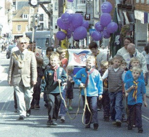 A group of young people escort a flame surrounded by dignitaries in Winchester High Street.
