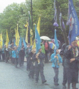 Scouts parading with flags in the rain.
