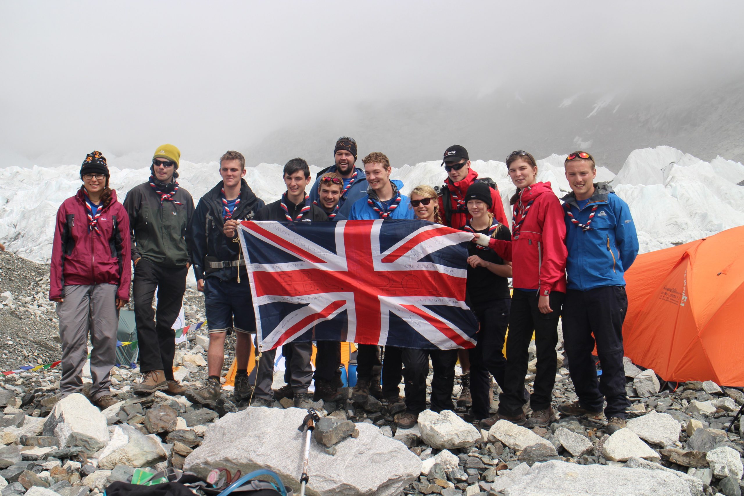 A group of Scouts stand near a glacier with a Union Flag